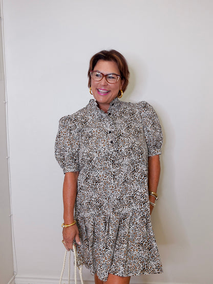Woman wearing a patterned dress against a white wall
