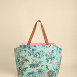 Floral-patterned tote bag with brown handles on a beige background