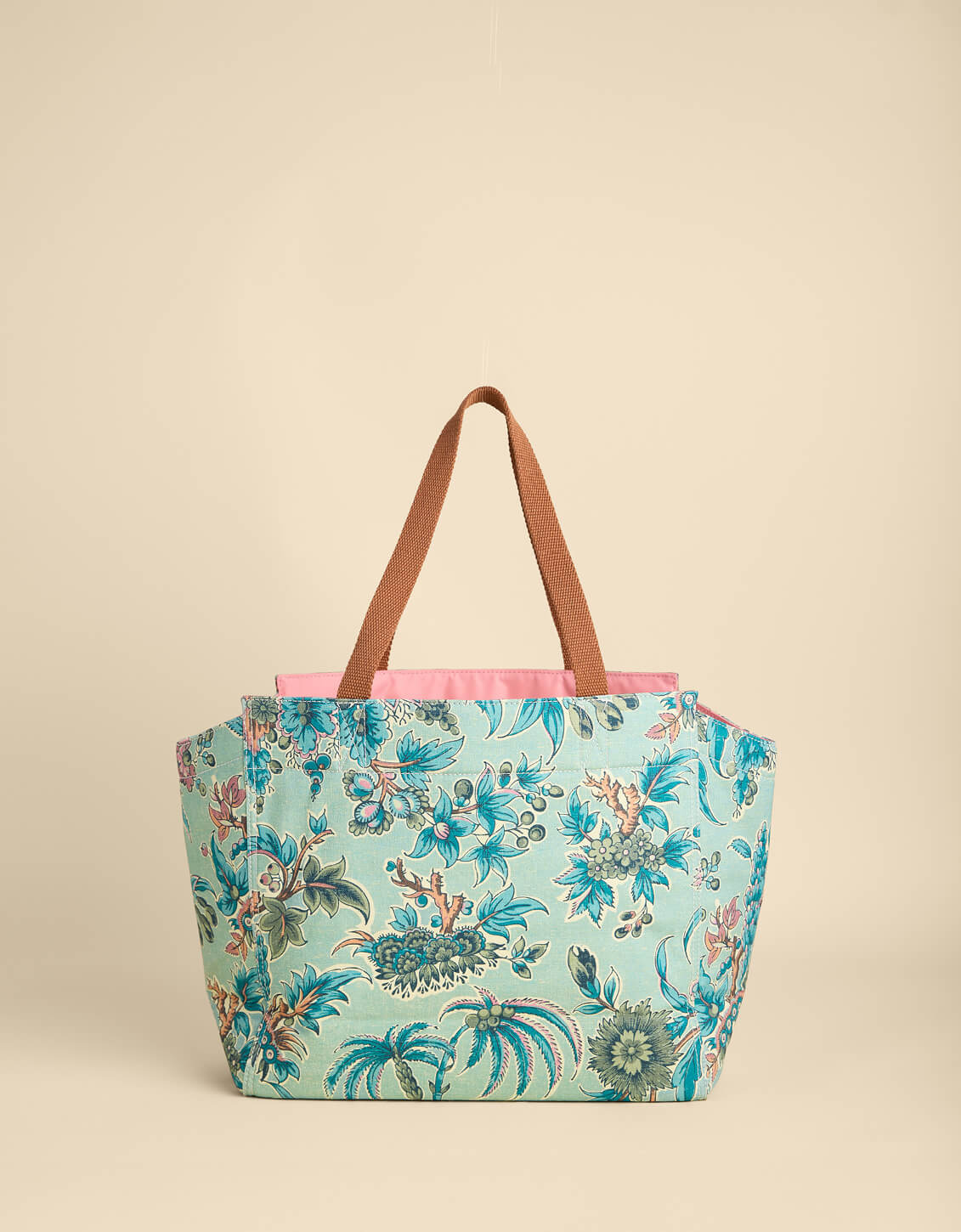 Floral-patterned tote bag with brown handles on a beige background