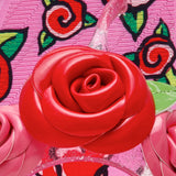 Close-up of a red rose-shaped object on a pink background with floral patterns