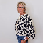 Person wearing a black and white checkered sweater against a plain background