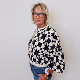 Person wearing a black and white checkered sweater against a plain background