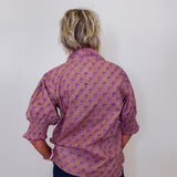 Person wearing a patterned shirt with their back to the camera against a plain background