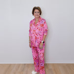Person wearing a pink floral pajama set against a white wall.
