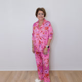 Person wearing a pink floral pajama set against a white wall.