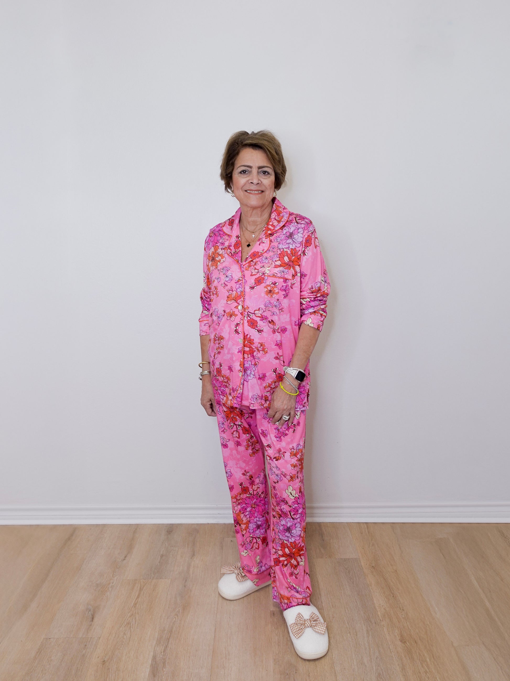 Person wearing a pink floral pajama set against a white wall.