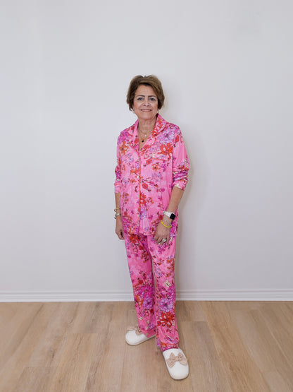 Person wearing a pink floral pajama set against a white wall.