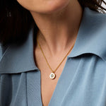 Close-up of a person wearing a gold necklace with a blue shirt.