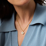 Close-up of a person wearing a gold necklace with a blue shirt.