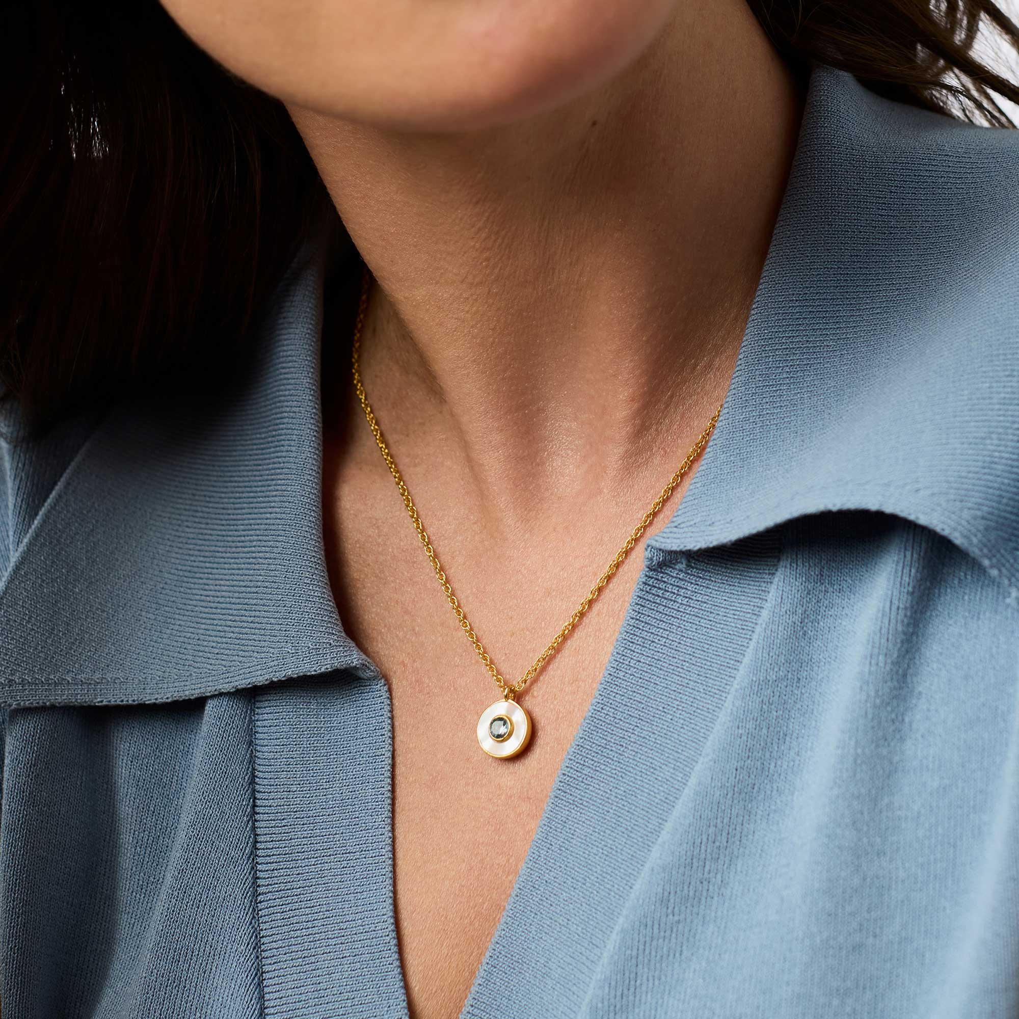 Close-up of a person wearing a gold necklace with a blue shirt.