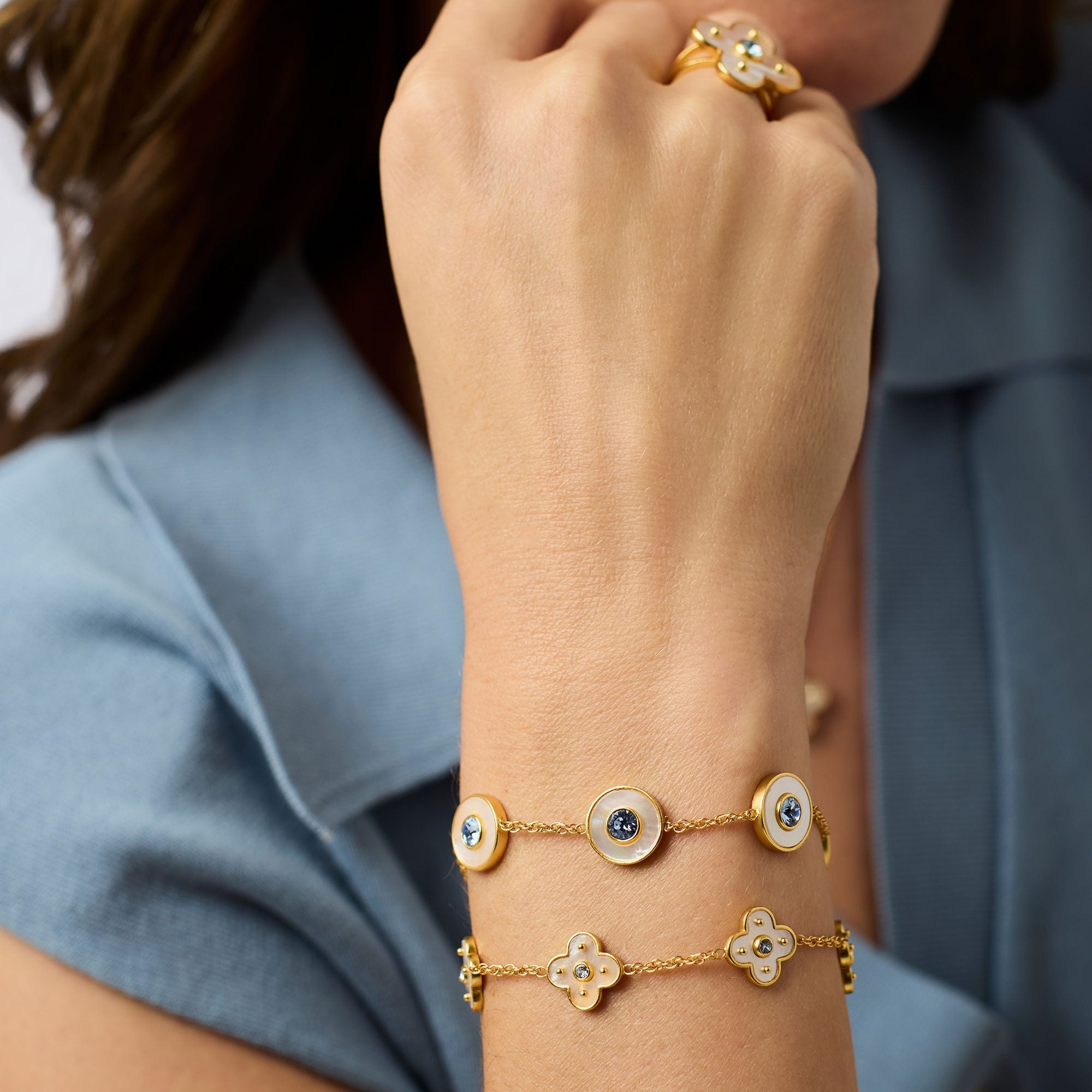 Gold bracelet with blue stones on a person's wrist against a blue shirt background
