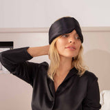 Woman wearing a black satin sleep mask indoors.