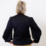 Person wearing a black jacket with puffed sleeves on a white background