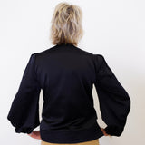 Person wearing a black jacket with puffed sleeves on a white background