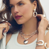 Woman wearing silver jewelry including earrings, necklace, and bracelet.