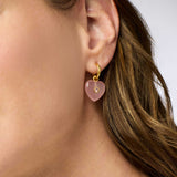 Heart-shaped pink earring with gold hoop worn by a person