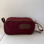 Red toiletry bag with a strap on a white background