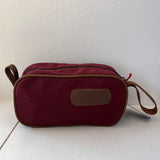 Red toiletry bag with a strap on a white background