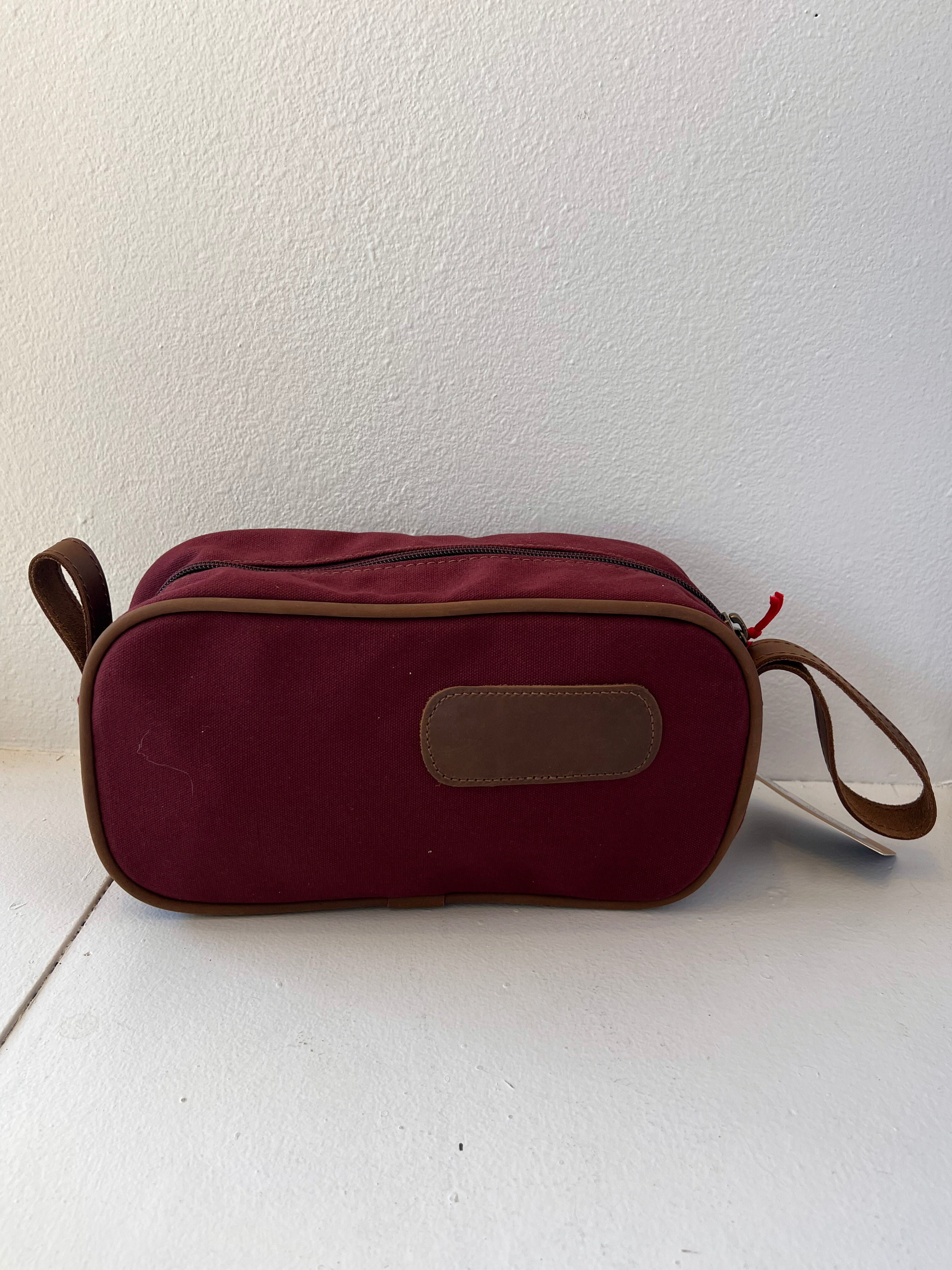 Red toiletry bag with a strap on a white background