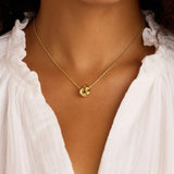 Gold necklace with a pendant worn by a person in a white blouse