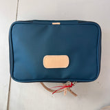 Blue toiletry bag with beige patch on a light surface