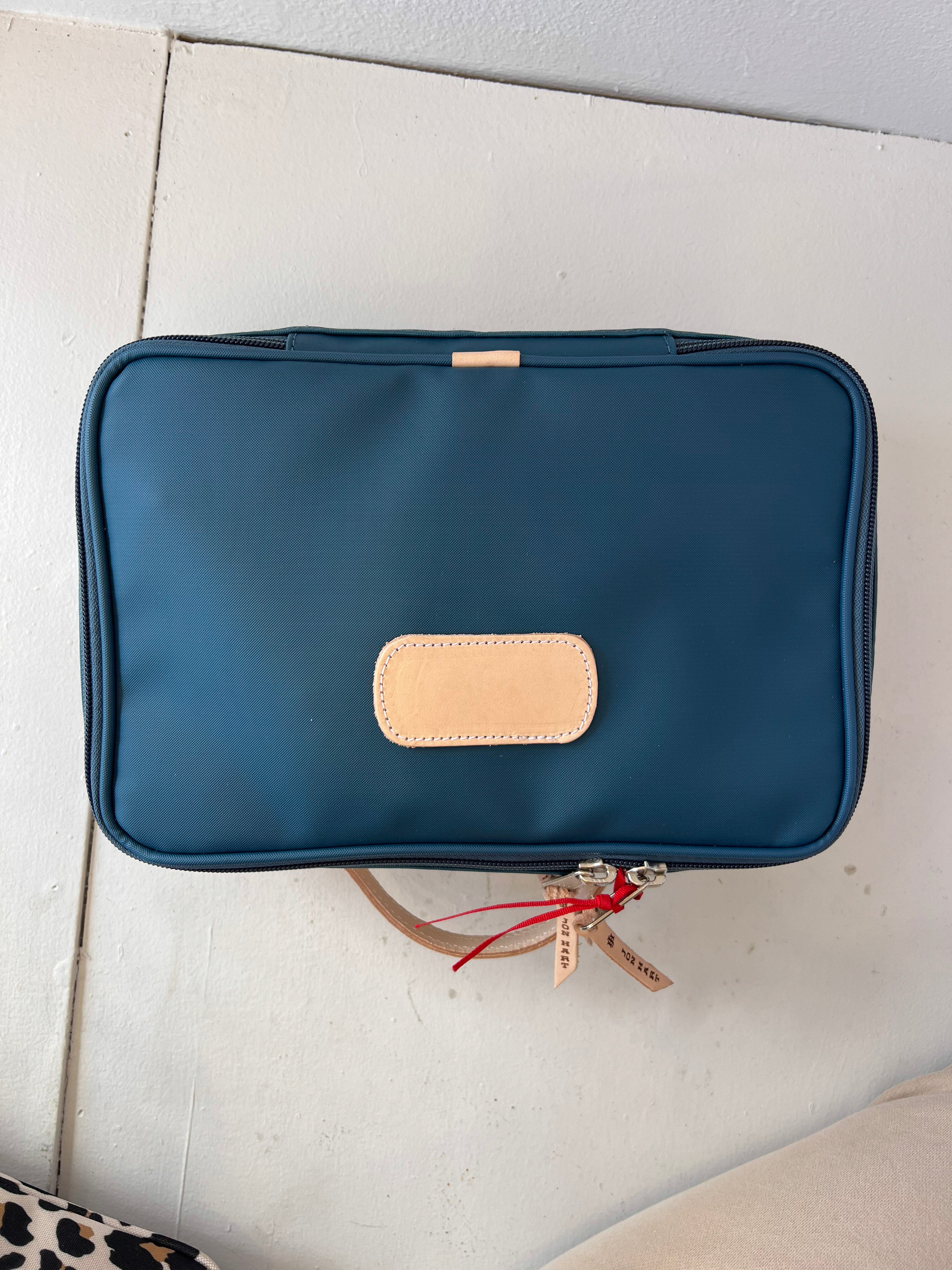 Blue toiletry bag with beige patch on a light surface
