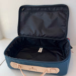 Open blue suitcase with beige handle on a white surface