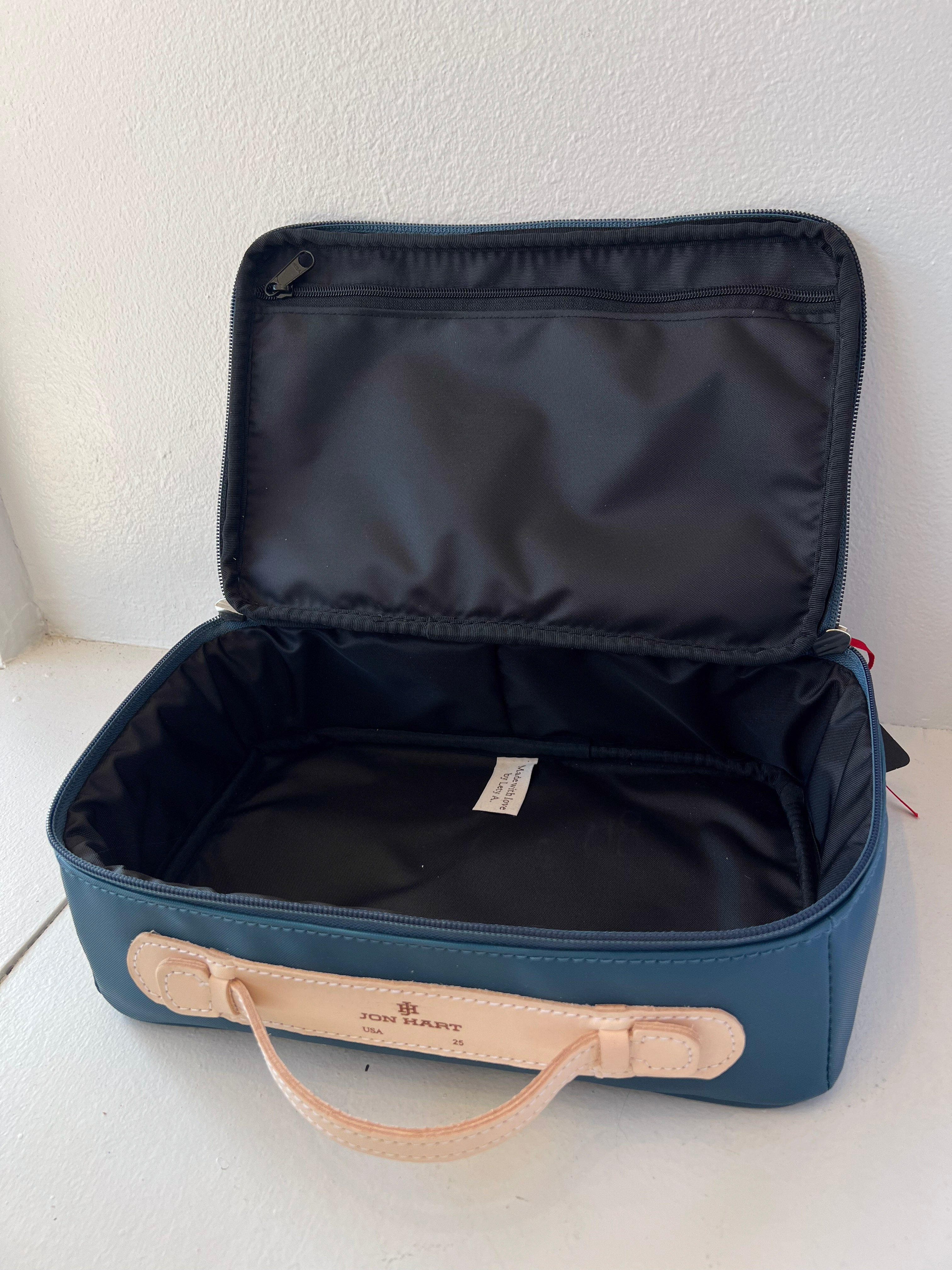 Open blue suitcase with beige handle on a white surface