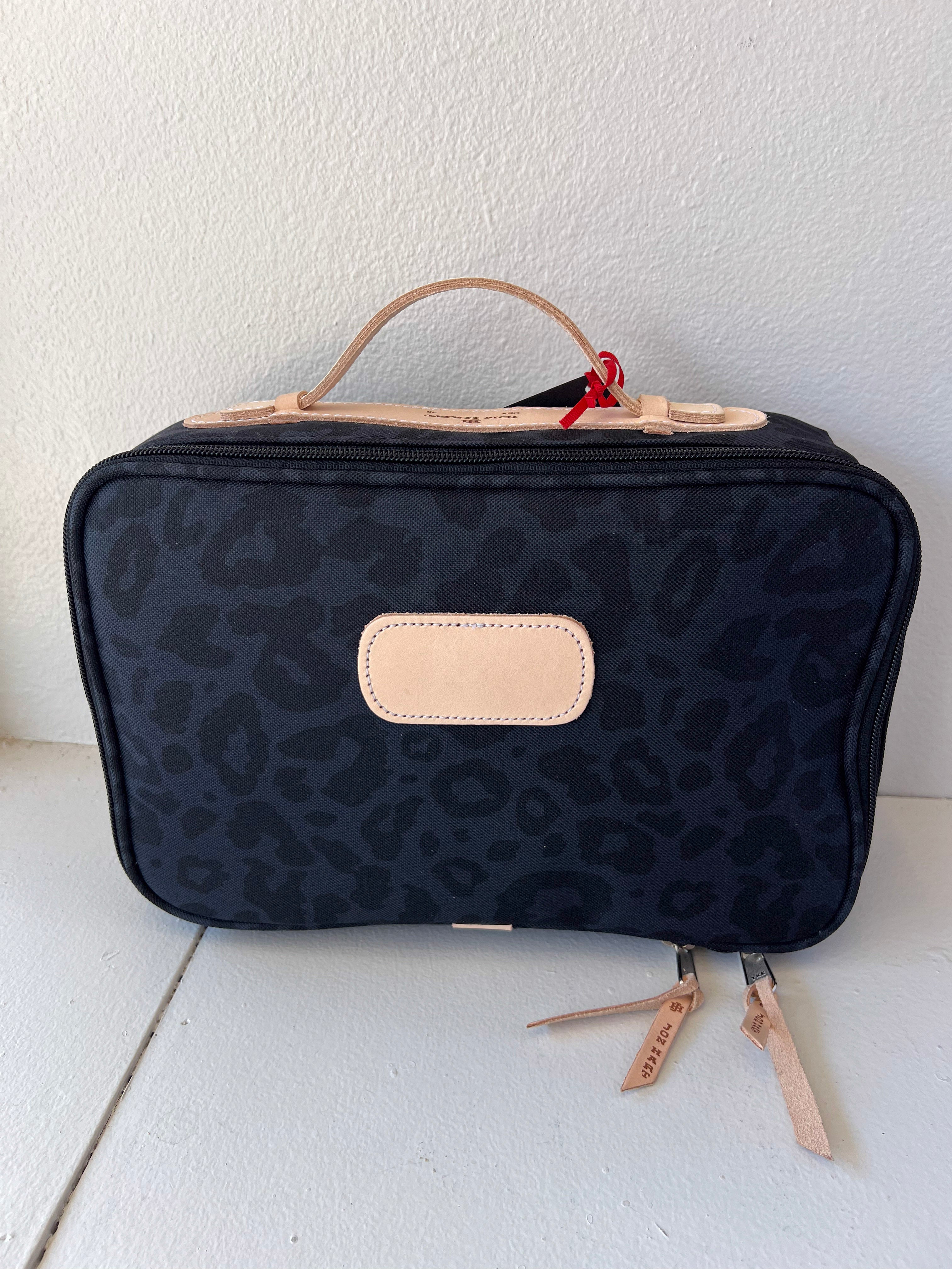 Black leopard print toiletry bag with beige accents on a white surface