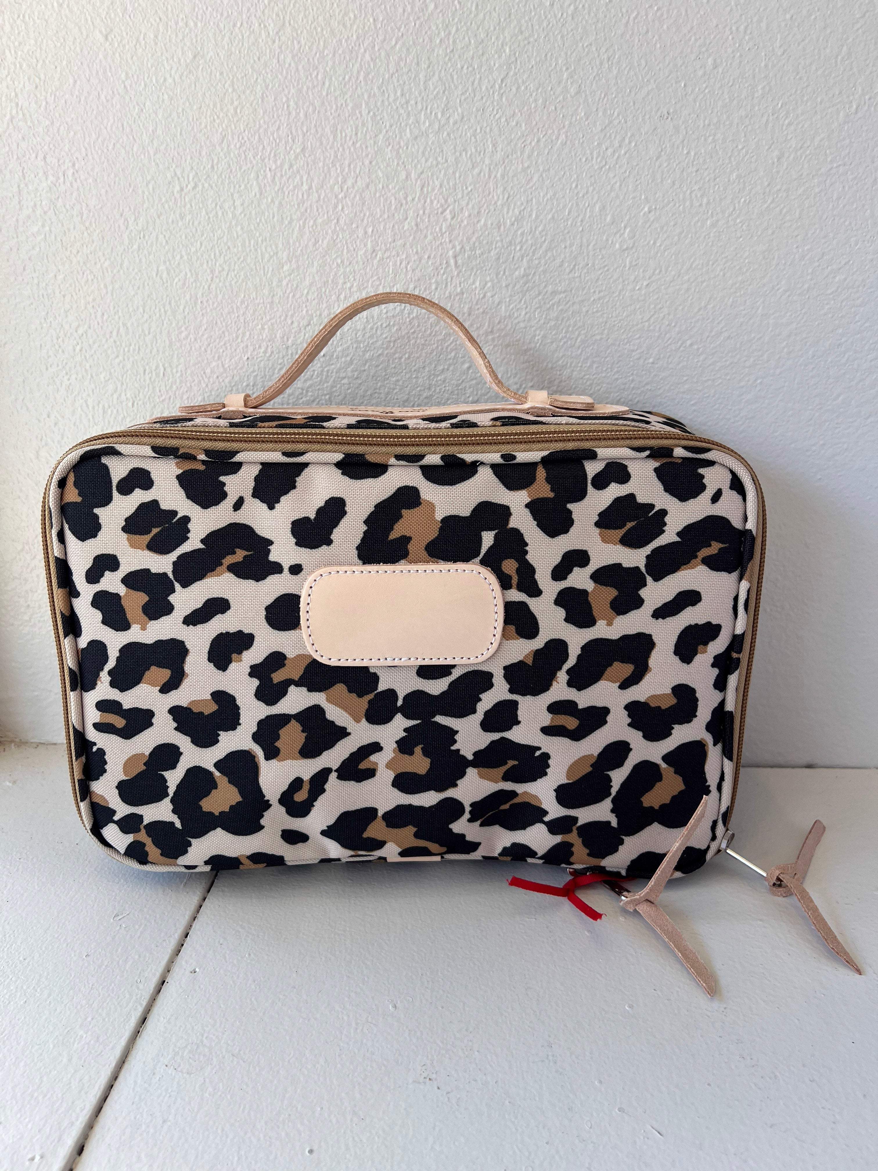 Leopard print travel bag on a white surface with a white background