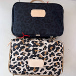 Two patterned bags, one black with leopard print and the other white with brown leopard print, on a light background.