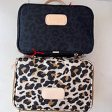 Two patterned bags, one black with leopard print and the other white with brown leopard print, on a light background.
