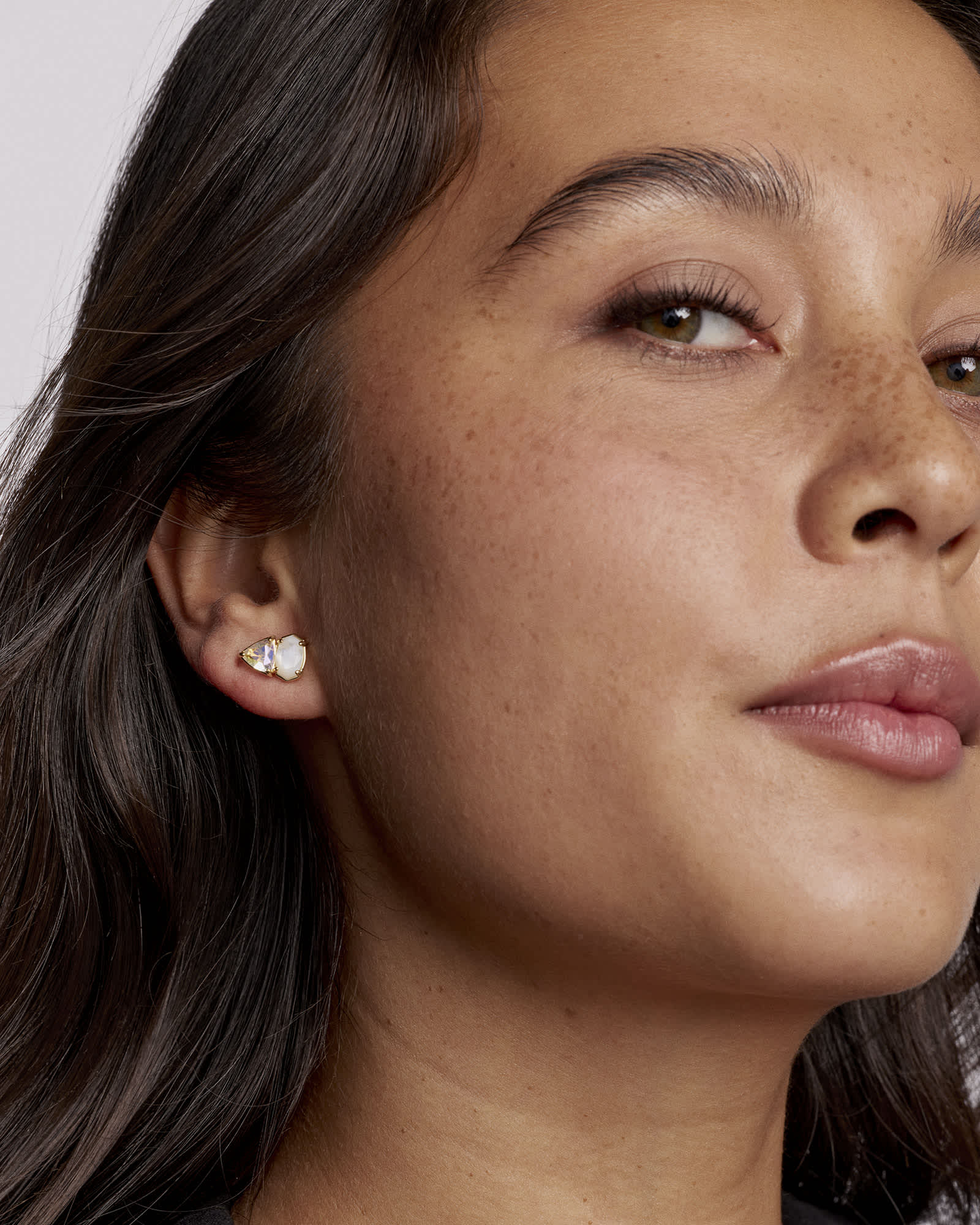 Close-up of a woman wearing a diamond earring with a plain background