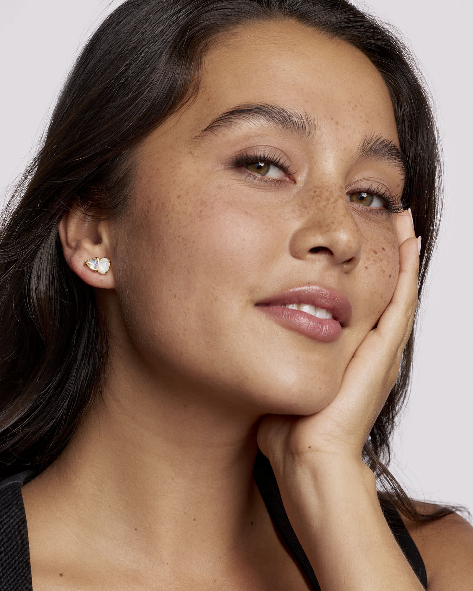 Woman wearing a heart-shaped earring with a plain background