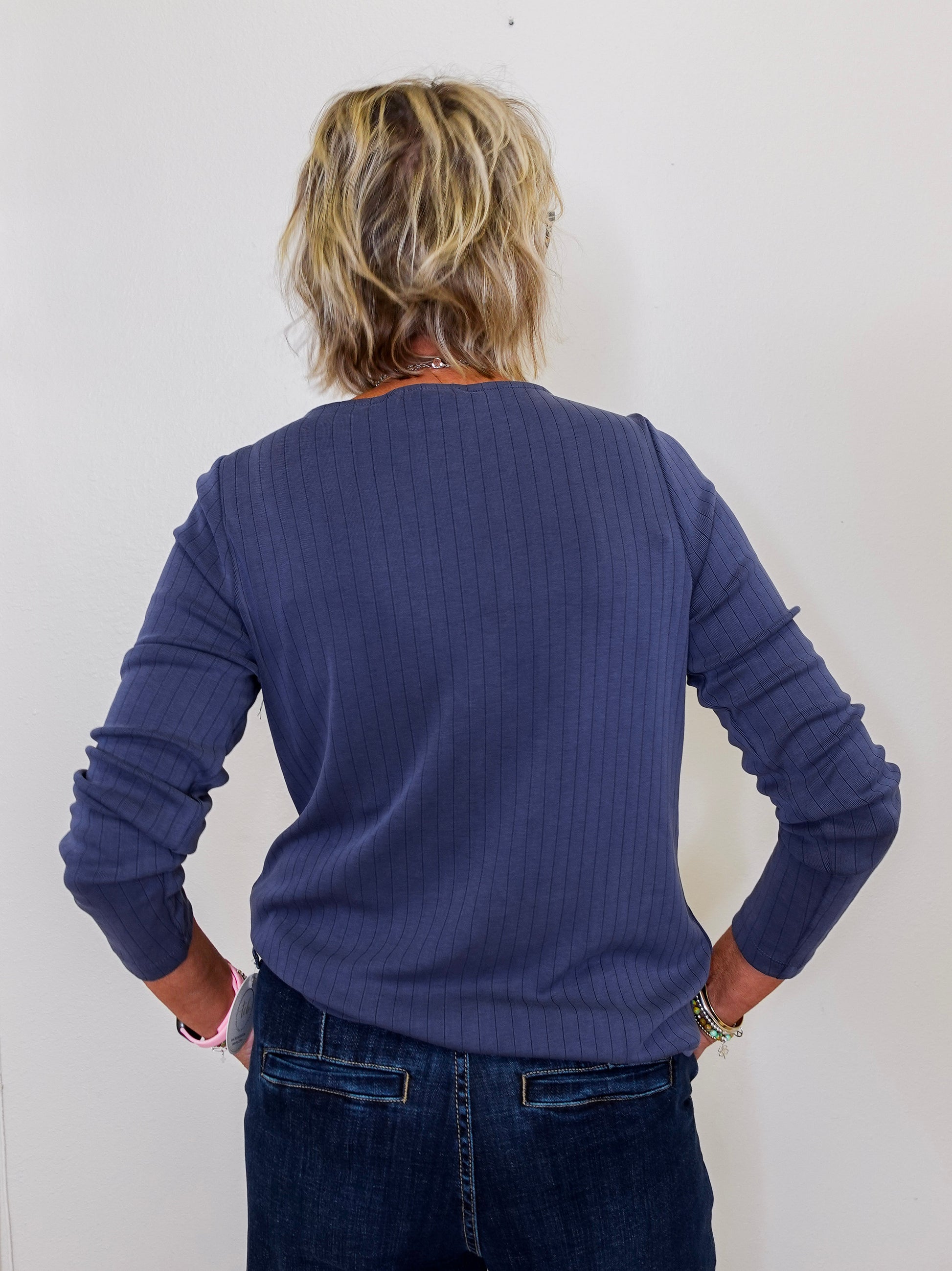 Person wearing a blue sweater and jeans against a white background