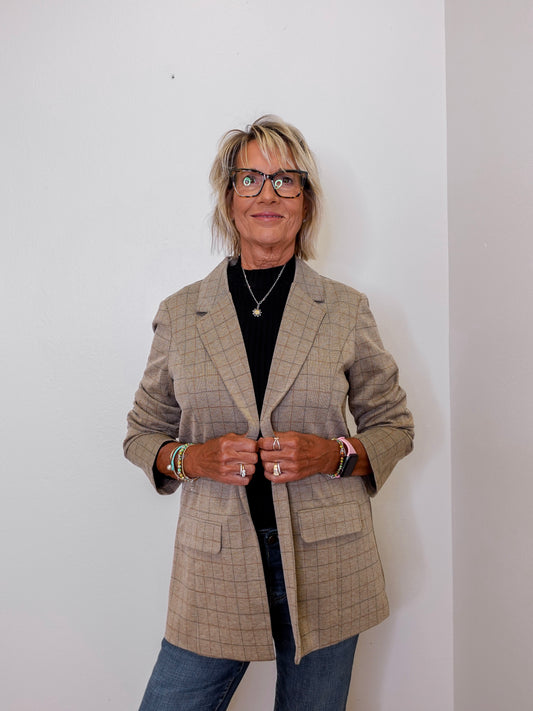 Person wearing a plaid blazer against a plain background