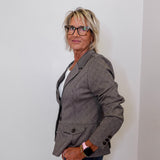 Woman wearing a brown blazer and glasses against a plain background