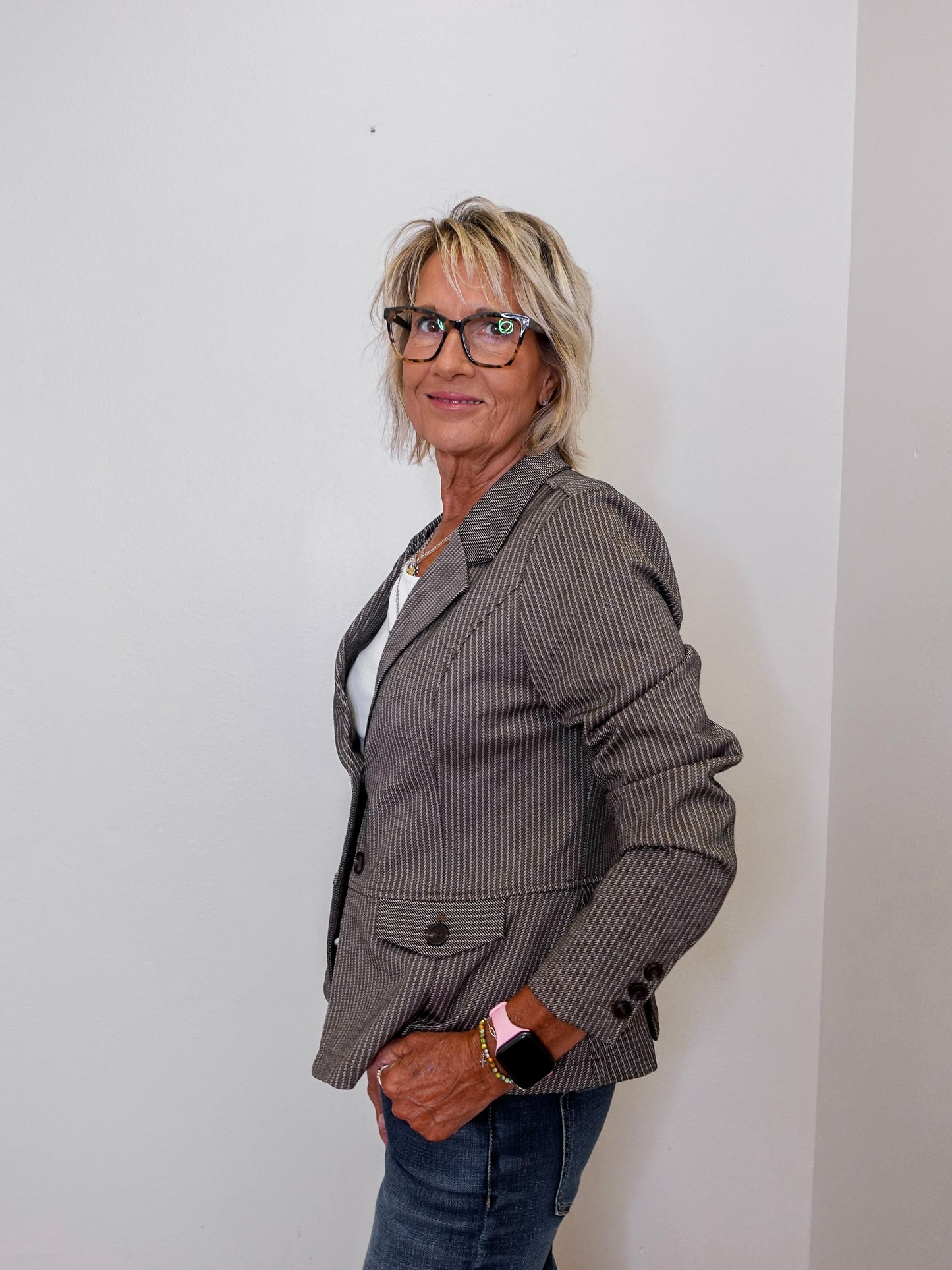 Woman wearing a brown blazer and glasses against a plain background