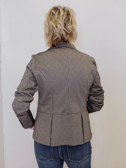 Person wearing a brown pinstripe jacket against a white background