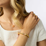 Woman wearing gold jewelry including a necklace, bracelet, and ring on a white background
