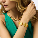 Woman wearing gold jewelry including a necklace and bracelets.