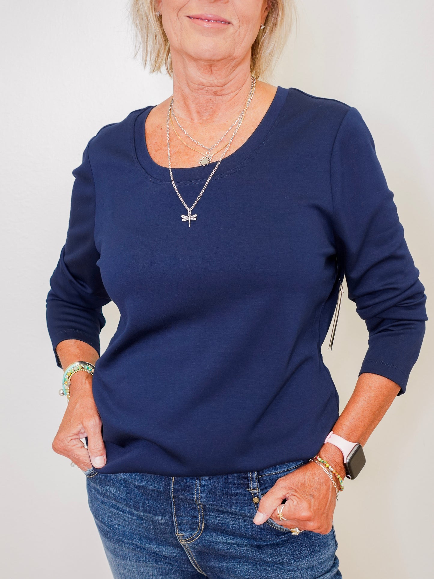 Person wearing a navy blue sweater and jeans against a plain background