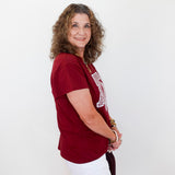 Woman wearing a red t-shirt with a logo and white shorts on a white background