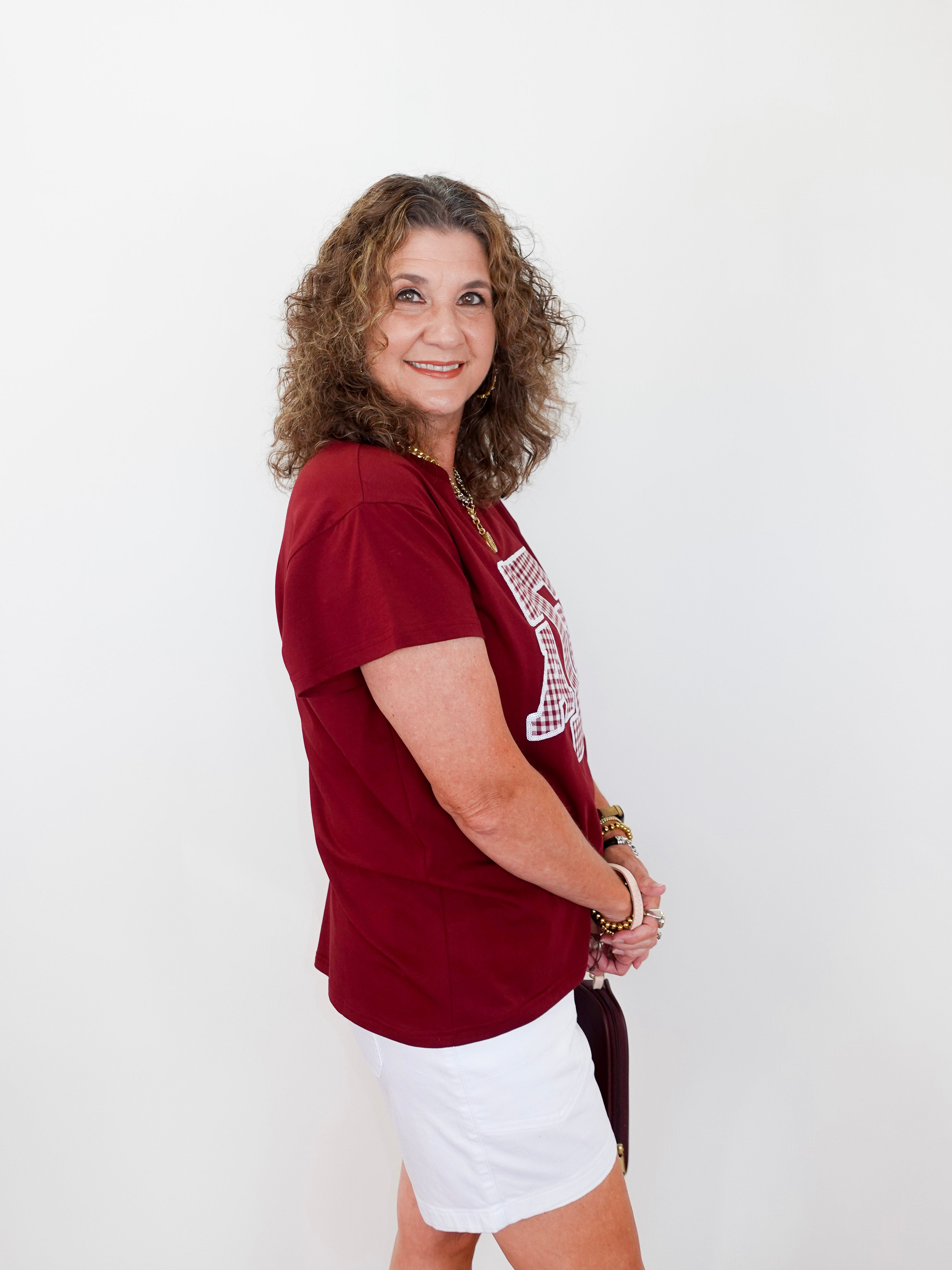 Woman wearing a red t-shirt with a logo and white shorts on a white background