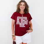 Woman wearing a red t-shirt with a logo and white shorts, holding a brown bag on a white background