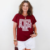 Woman wearing a red t-shirt with a logo and white shorts, holding a brown bag on a white background