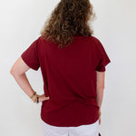 Person wearing a red shirt and white shorts against a plain background