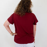 Person wearing a red shirt and white shorts against a plain background