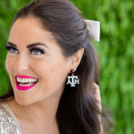 Woman wearing Aggie earrings with a green blurred background
