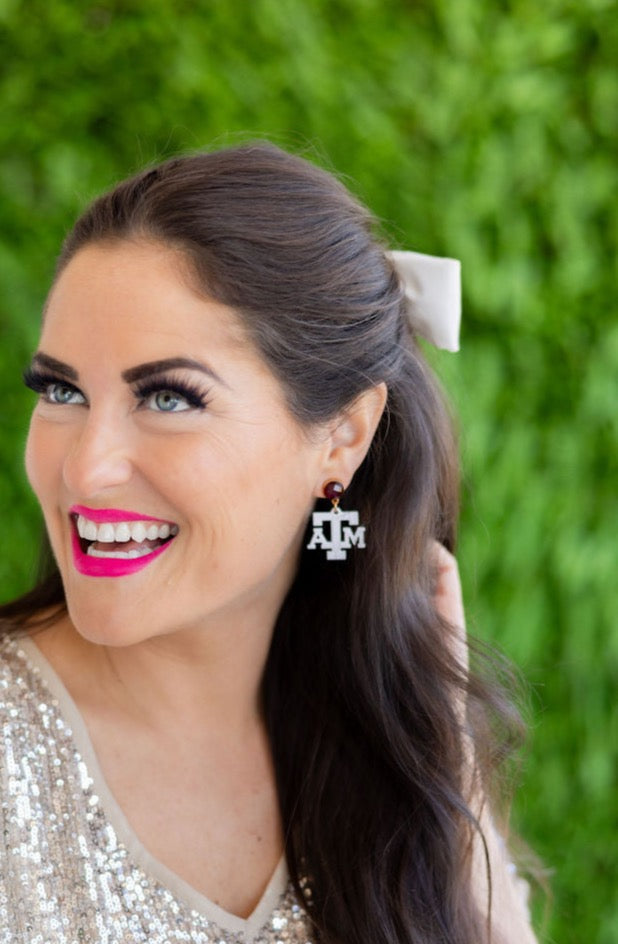 Woman wearing Aggie earrings with a green blurred background